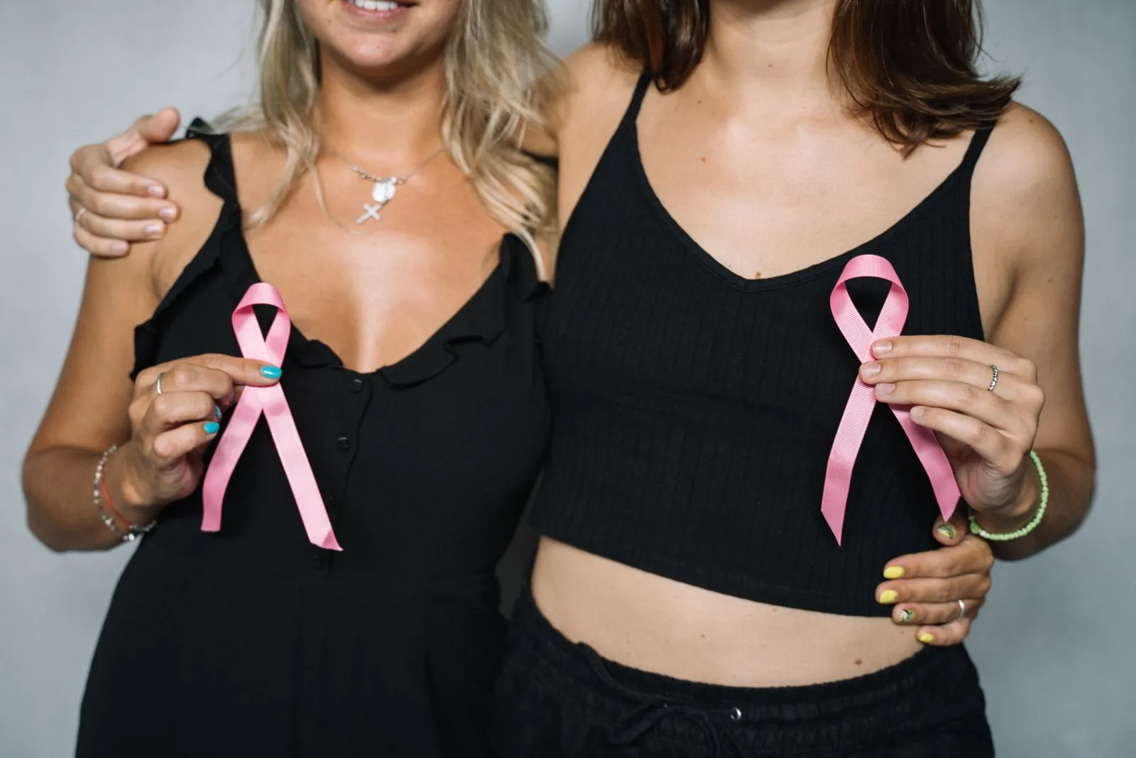 Dos mujeres abrazadas sostienen lazos rosas, símbolo de la lucha contra el cáncer de mama