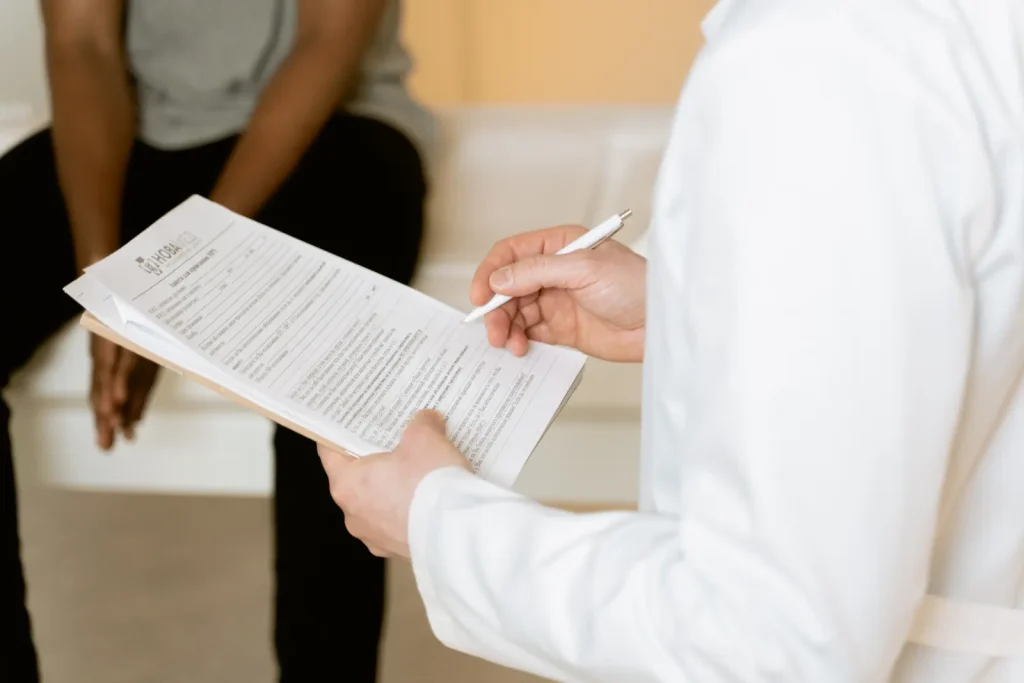 Profesional de la salud revisa un formulario mientras una paciente espera sentada