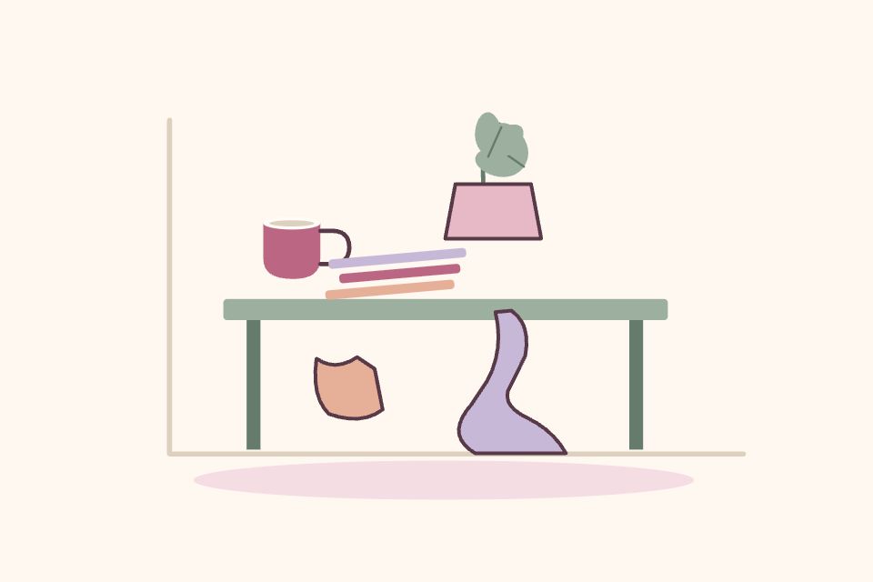 Rincón cotidiano con taza, libros desalineados, planta y una tela sobre la mesa, sin decoración perfecta.
