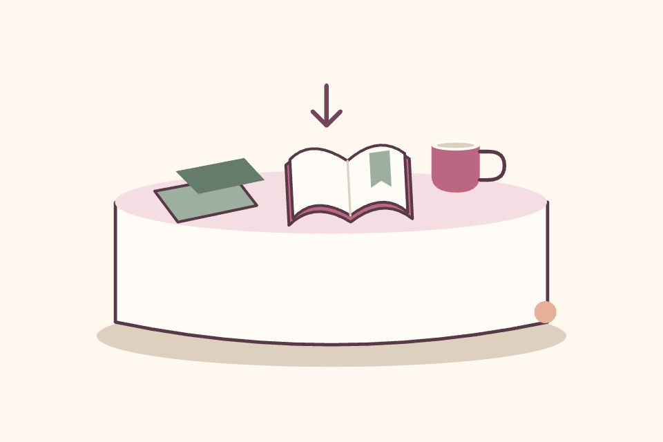 Bandeja con un tapete plegado, un libro abierto y una taza, con una flecha suave que invita a elegir.