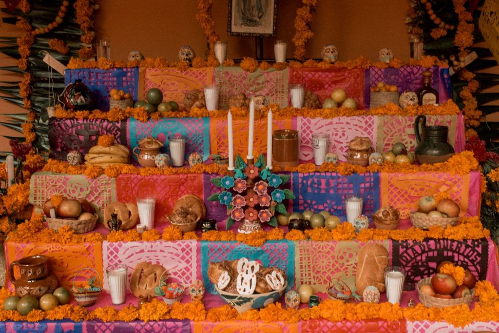Altar de Día de Muertos en Puebla, México, con flores de cempasúchil, papel picado, velas y ofrendas.