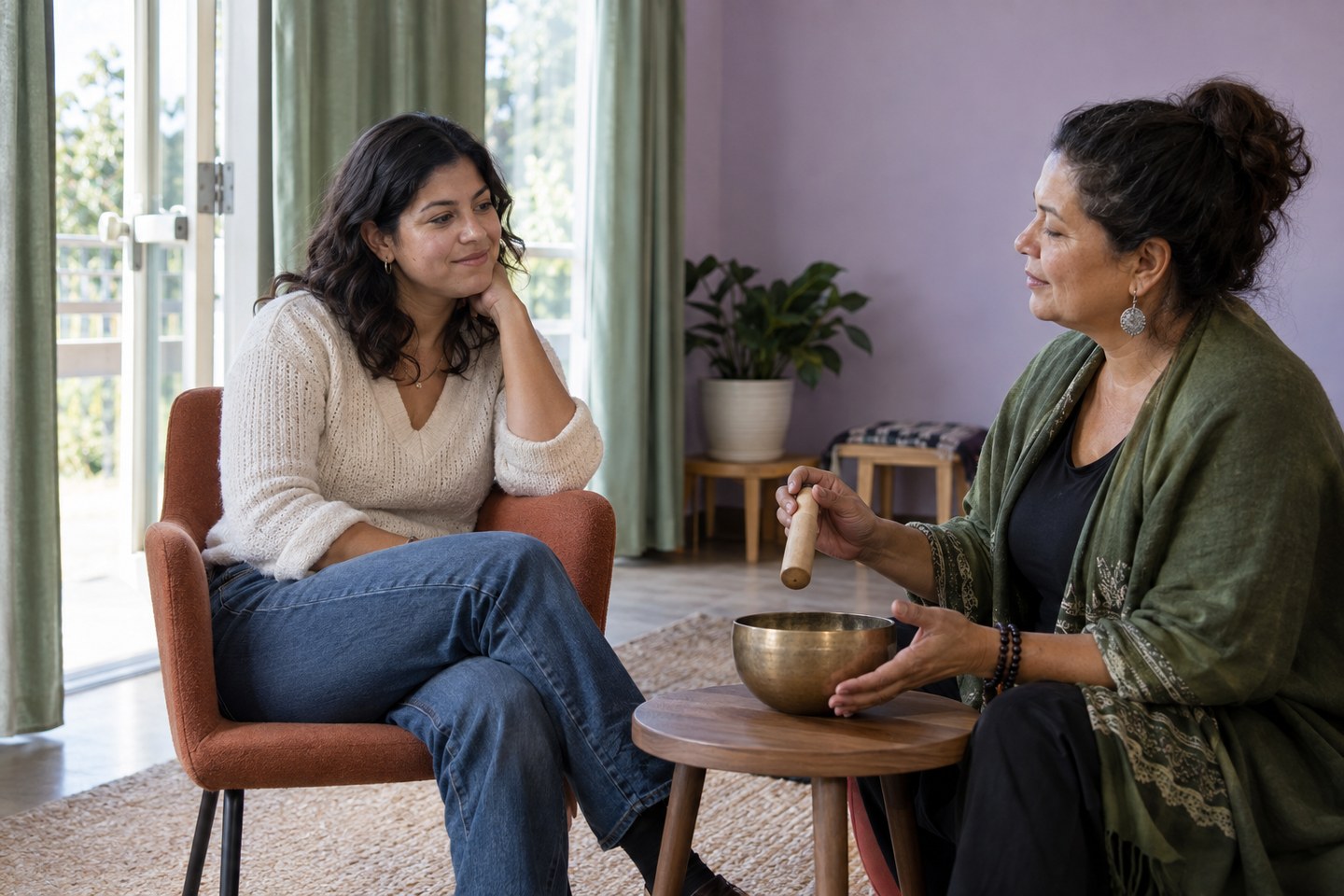 Dos latinas adultas en una sala comunitaria, junto a una silla y un cuenco de sonido. Imagen editorial generada con IA; personas ficticias.