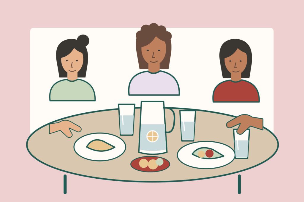 Tres amigas comparten una mesa con vasos de agua, cítricos, una jarra y comida sencilla.
