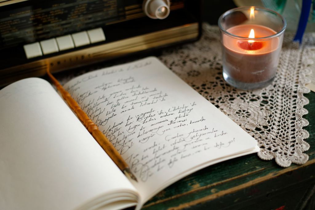 Cuaderno abierto con notas escritas a mano junto a una vela encendida.