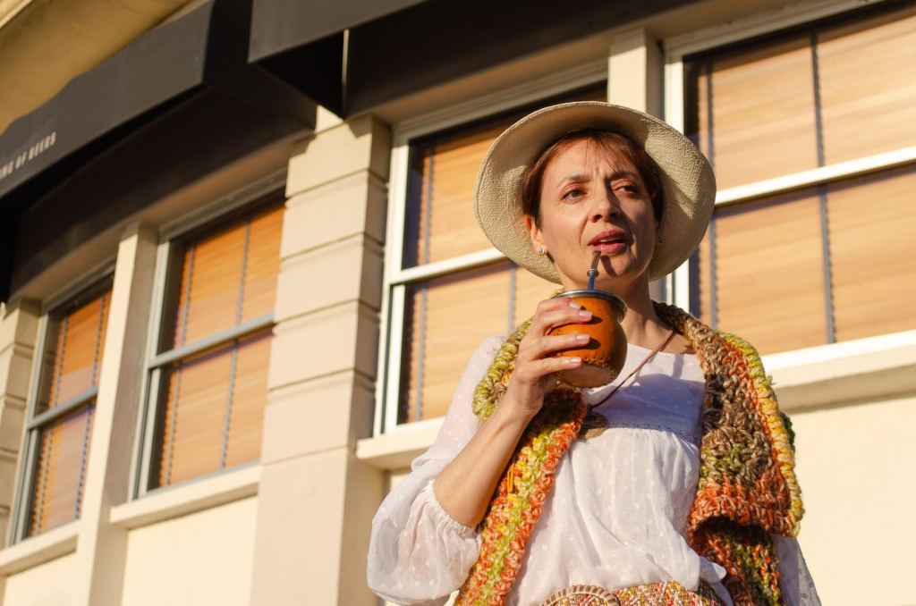 Mujer con sombrero toma mate bajo el sol en Montevideo.