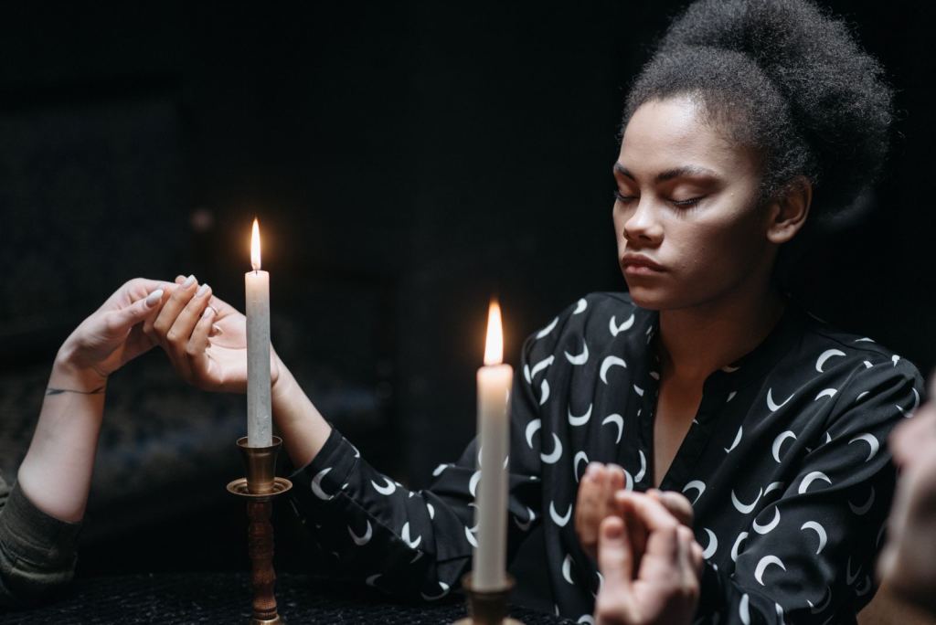 Mujer con los ojos cerrados medita a la luz de varias velas encendidas.