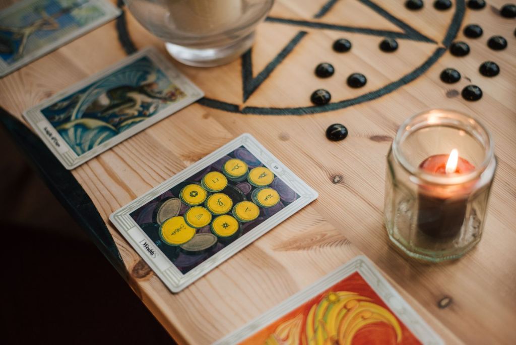 Cartas de tarot sobre una mesa de madera junto a una vela encendida.
