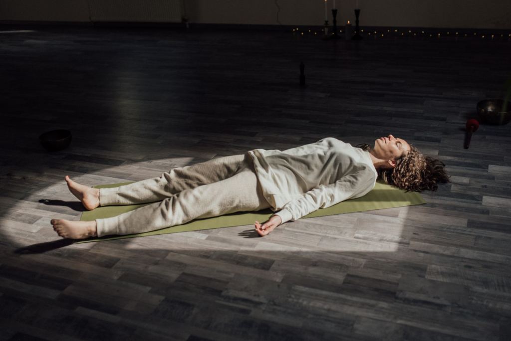 Mujer acostada sobre un tapete de yoga, relajada, en una sala tranquila.